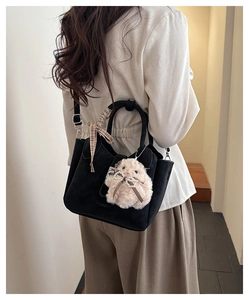 Détail d'un sac noir en daim avec écharpe en soie à carreaux et pendentif lapin rose