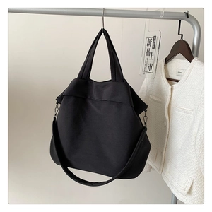 Détail d'un grand sac fourre-tout en nylon noir avec bandoulière réglable et boucles en métal