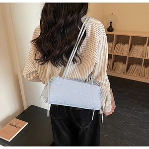 Detail of light blue baguette bag featuring silver stars and side decorative straps