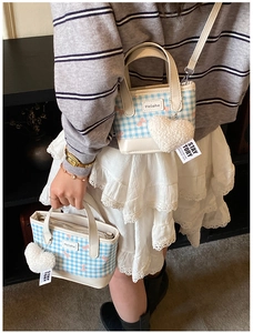 Blue plaid mini tote bag detail with pink bow print and white plush heart charm