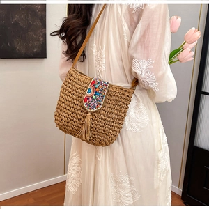 Detail view of bohemian straw crossbody bag with colorful bead embroidery and long tassels