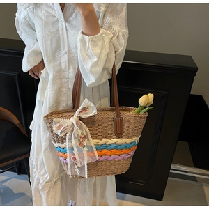 Detail of hand-woven straw tote with large white lace flower and brown leather straps