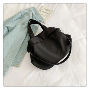 Vue de dessus d'un sac cabas en nylon noir minimaliste avec veste en jean et livre