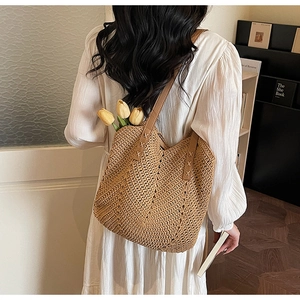 Close-up of a handmade woven straw beach tote bag with brown faux leather shoulder straps