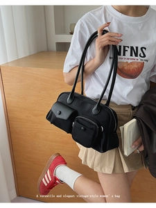 Close-up of black retro functional underarm bag with functional pockets and silver zippers
