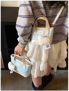 Close-up of mini bucket bag with blue plaid pattern, pink bow, and plush heart charm