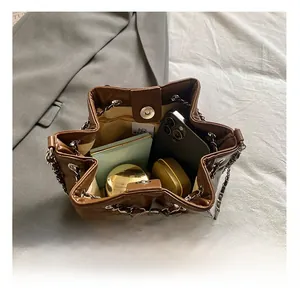 Macro detail of brown quilted bucket bag with chain strap showing interior storage capacity