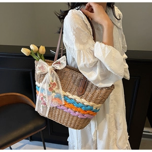 Detail of woven straw tote bag featuring colorful bands and floral embroidery lace bow