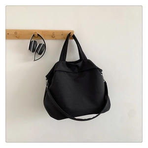 Détail d'un grand sac cabas en nylon noir accroché à un crochet avec un casque
