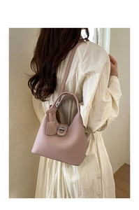 Detail of dusty pink lychee leather bucket bag with metal lock and shoulder strap