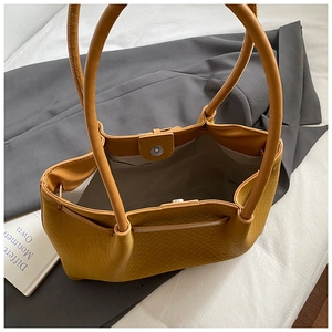 Detail of the yellow woven tote bag showing the magnetic buckle and interior zipper pocket