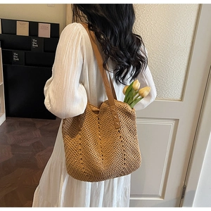 Detail of woven straw tote bag featuring brown leather straps and intricate openwork texture