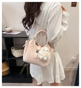 Détail du sac seau en cuir rose clair avec nœud ruban et pendentif lapin en peluche