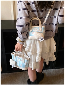 Blue checkerboard mini bucket bag with pink bow prints and heart plush charm on model