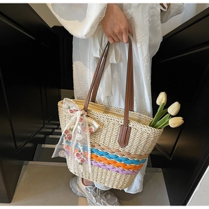 Close-up of handmade straw tote featuring colorful braided trim and lace flower pendant