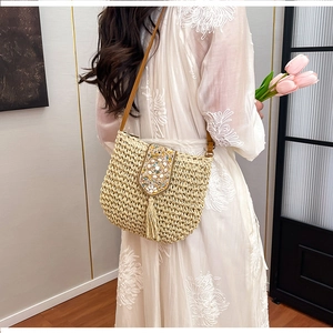 Detail of bohemian straw bag with floral beadwork embroidery and tassel fringe