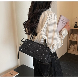 Detail of black baguette bag with white star pattern and stylish side ribbon bows