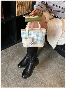 Close-up of mini canvas bucket bag with blue plaid patterns and cute pink bow details