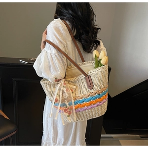 Detail of woven straw tote with colorful braided base and floral lace scarf detail
