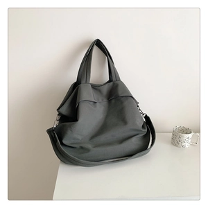 Détail d'un grand sac fourre-tout en nylon gris foncé avec crochets et bandoulière amovible