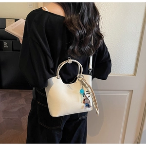 Détail du sac seau crème avec foulard en soie tissé et pendentif de dessin animé mignon