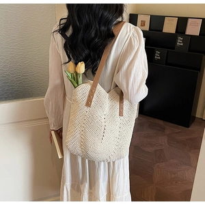 Close-up of woven tote bag featuring beige V-pattern texture and brown leather straps