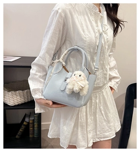 Gros plan du sac seau bleu clair en cuir avec poignée foulard et breloque mouton peluche