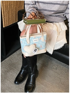 Close-up of blue gingham mini bucket bag with pink bow and heart plush pendant