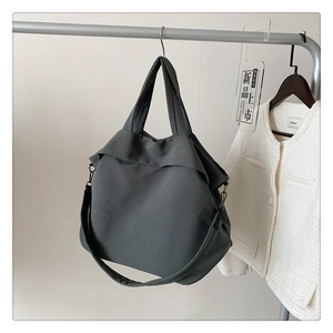Détail du sac cabas en nylon gris montrant la texture souple et la bandoulière réglable
