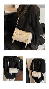 Detail view of cream white patent leather bowling bag with metallic hardware and zippers