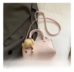 Pink leather Boston bag detail with plush bear charm and crossbody strap on gray suit