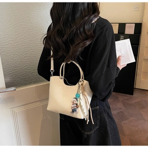 Détail du sac seau crème avec breloque ours et décoration de sangle tissée sur le côté