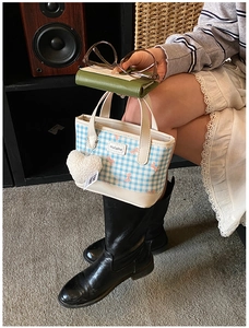 Detail view of mini blue gingham tote bag with bow pattern and heart plush charm