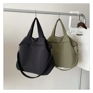 Détail de grands sacs fourre-tout en nylon noir et vert olive avec larges bandoulières