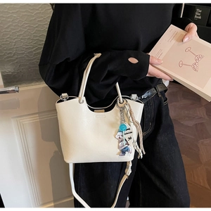 Détail du sac seau blanc crème avec bord ondulé et breloque ours décorative