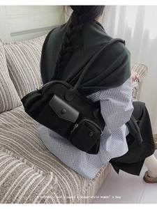 Detail of a vintage black multi-pocket shoulder bag shown on a model sitting on a sofa