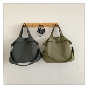 Détail de grands sacs fourre-tout en nylon gris et vert olive suspendus à des crochets