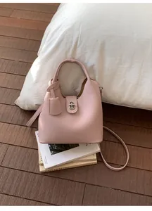 Detailed macro view of soft pink litchi grain leather texture and metallic lock closure