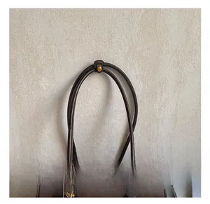 Detailed close-up of dark brown leather handbag handle with gold snap button