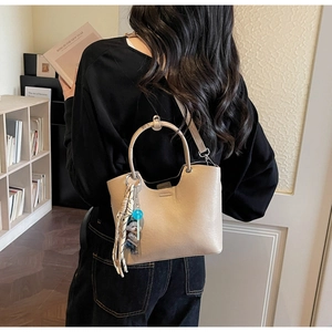 Vue détaillée du sac seau beige avec poignée ronde et accessoire en soie