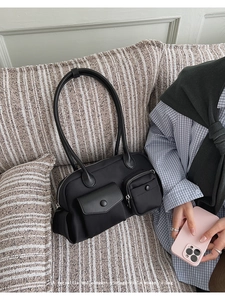 Detail of black nylon shoulder bag with dual functional pockets on striped fabric