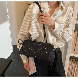 Minimalist black baguette shoulder bag with white star pattern in a cozy indoor setting
