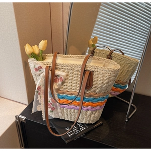 Detail view of woven straw tote bag featuring colorful bands and a lace flower bow