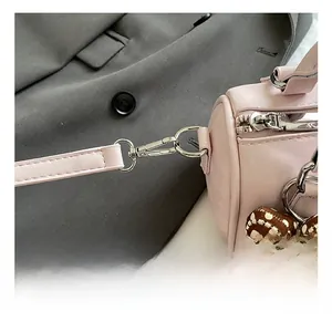Detail of pink pebbled leather bag with gold metal hook and polka dot bear charm