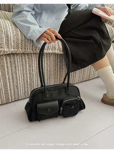 Detail view of a vintage black shoulder bag with multi-pocket design on a striped sofa