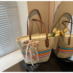 Detail of hand-woven straw tote bag with multi-colored stripes and lace ribbon handle bow