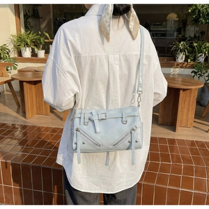 Close-up of light blue bowling bag featuring dual zippers, metal buckles, and studs detail