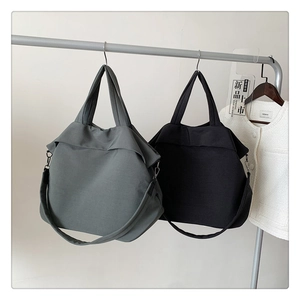 Détail de grands sacs fourre-tout en nylon gris et noir avec de larges bandoulières amovibles
