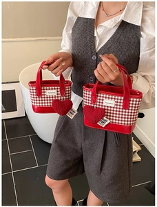 Detail shot of checkered bucket bags with red heart charms and stylish Helahe logo leather patch