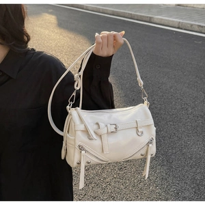 Detail of a beige moto-style bowling bag with tassel zippers and cross straps